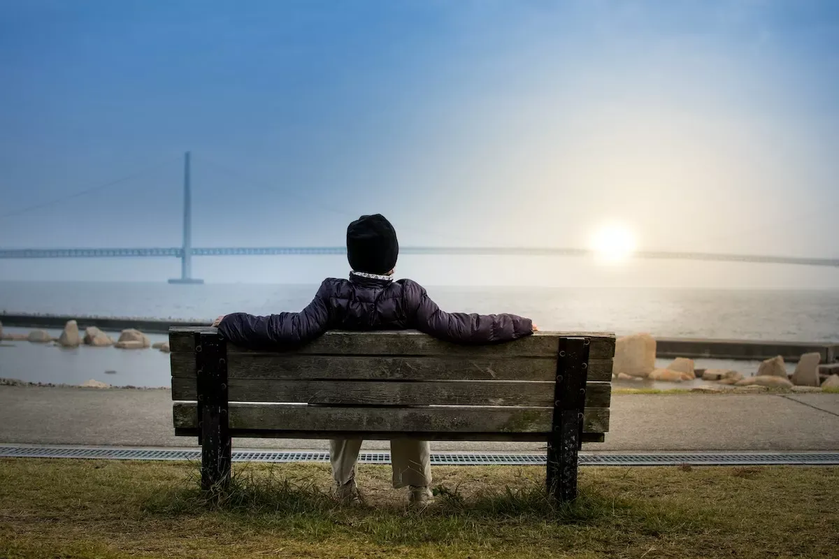 A man sitting on a bench in front of a lake