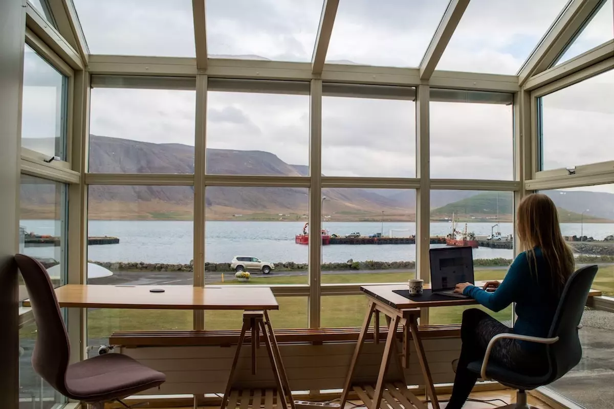 A person working from a veranda with a view of a lake and mountains