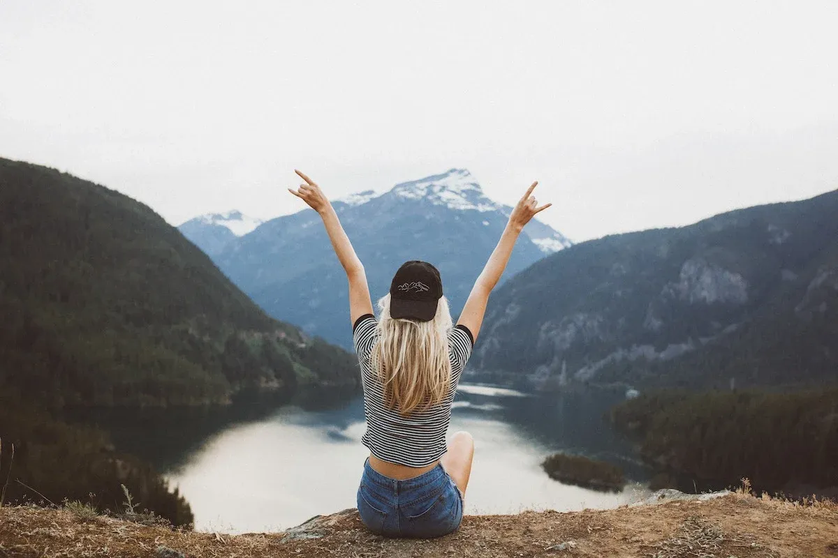 A woman raising her arms on top of a cliff