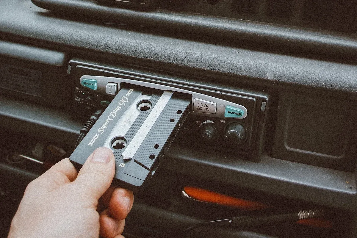 A person inserting an audio tape into a car